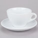A close up of a CAC white cup and saucer with a gray surface.
