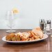 An Elite Global Solutions oval plate with pasta and meatballs on a table.