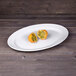 An Elite Global Solutions white oval melamine platter with cut up oranges on it.
