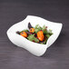 A white Elite Global Solutions square melamine bowl filled with salad and orange peppers.