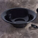 An Elite Global Solutions black flared bowl on a marbled surface with a spoon inside.