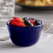 A Tuxton cobalt bouillon cup filled with fruit on a table.
