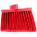 A red Carlisle broom head with long, red flagged bristles.