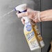 A person wearing a plastic glove spraying Bar Keepers Friend All Purpose foam cleaner from a bottle.