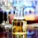 A Fineline clear plastic mini wine carafe filled with yellow liquid on a table.