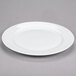 A 10 Strawberry Street Bistro bright white porcelain charger plate with a rim on a gray surface.
