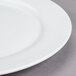 A close up of a 10 Strawberry Street Bistro bright white porcelain charger plate with a rim.