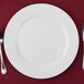 A 10 Strawberry Street Bistro bright white porcelain charger plate with silverware on it.