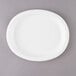 A white oval Creative Converting paper platter on a gray surface.