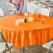 A table with Sunkissed Orange OctyRound tablecloths and glasses of liquid on it.