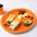 A sandwich on a Sunkissed Orange oval paper platter with carrots and broccoli.