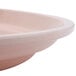 A light peach Cambro oval tray with a white rim on a counter.