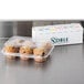 A plastic container of muffins next to a Noble Products 7-Slot Dispenser with 7 rolls of food rotation labels.