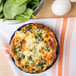 A baked spinach and cheese quiche in a blue CAC quiche dish.