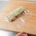 A hand cutting a sandwich in a LK Packaging plastic sandwich bag.
