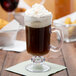 A GET Tritan plastic Irish coffee mug filled with coffee and whipped cream on a white surface.