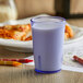 A close up of a blue GET SAN plastic tumbler filled with milk on a table.