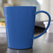 A Carlisle Ocean Blue Tritan mug on a table.