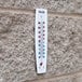 A Taylor wall thermometer on a brick wall with the temperature at 8 degrees.