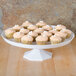 A Fineline white cake stand with cupcakes on it.