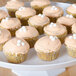 A Fineline white cake stand holding cupcakes with white frosting and white balls.