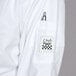 A Chef Revival white long sleeve chef coat with a pocket and pen inside.