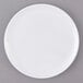 A white Carlisle melamine plate with a white rim on a gray surface.