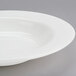A Homer Laughlin wide rim china soup bowl in white on a gray surface.