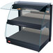 A black Hatco countertop merchandising warmer with curved glass shelves and a glass door.