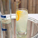 A Libbey Collins glass filled with lemonade and a slice of orange on a silver tray.