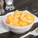 A Dart insulated white foam bowl filled with macaroni and cheese on a wooden table.