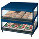 A navy blue Hatco countertop food warmer with food on slanted shelves on a counter.