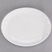 A Tuxton oval china platter with a white center and rim on a gray surface.