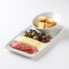 A Tuxton bright white rectangular china tray with meat, olives, and cheese and a bowl of bread slices.