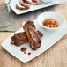 A Tuxton bright white rectangular china tray with ribs and beans.