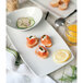 A Tuxton white rectangular china tray with food including salmon and cucumber.