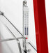 A thermometer on a metal shelf with a red handle inside a Hatco warm red stainless steel countertop merchandiser.