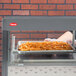 A person in gloves putting French fries in a Hatco countertop hot food display.
