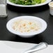 A white Thunder Group narrow rim melamine monkey dish filled with coleslaw on a table.