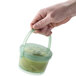 A hand holding a jade green GET Reusable Eco-Takeout Soup container.