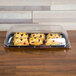 A Sabert clear plastic catering tray with a high dome lid over pastries.