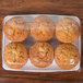 A plastic container with muffins on a counter.