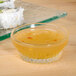 A clear Libbey Winchester glass ramekin filled with sauce on a table with sushi.