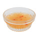 A clear Libbey Winchester glass ramekin filled with orange liquid with chili peppers.