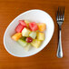 A Tuxton Capistrano bowl filled with sliced fruit on a table.