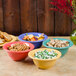 A group of GET Rio orange melamine bowls filled with food on a table.