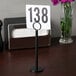 A Tablecraft black flat bottom menu / card holder with a table number.