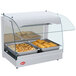 A Hatco white curved glass countertop food warmer with trays of food in it.