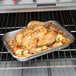 A Vollrath stainless steel roasting pan with chicken and vegetables in the oven.