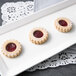 A white rectangular porcelain platter with three cookies, one with jam.